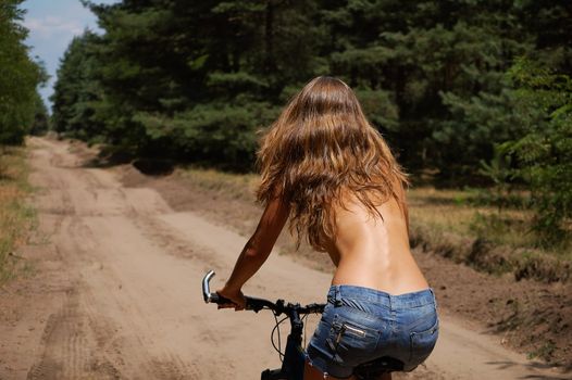 the girl with the bike for a walk in the woods on a sandy road