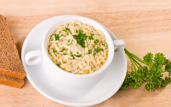 Noodles and parsley soup on plate, bread