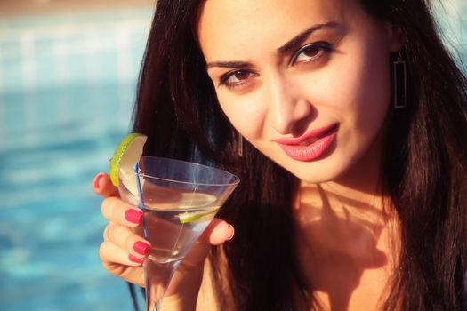 Attractive, young female holding a glass and drinking martini cocktail