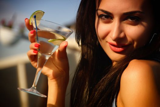 Attractive, young female holding a glass and drinking martini cocktail