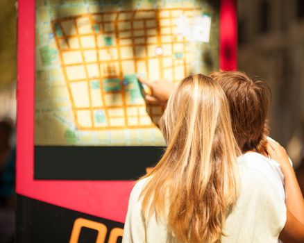 Woman and man watching a map on the street of an european city