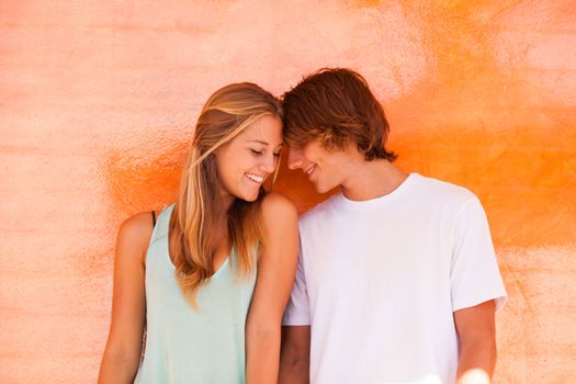 Young beautiful couple having great time over orange background