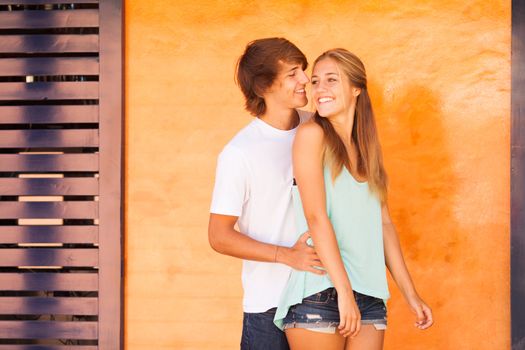 Young beautiful couple having great time over orange background