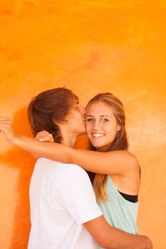 Young beautiful couple having great time over orange background