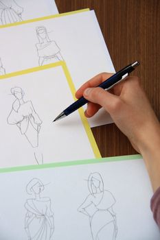 designer assessing fashion drawings on the collection of clothes