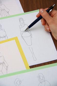 designer assessing fashion drawings on the collection of clothes