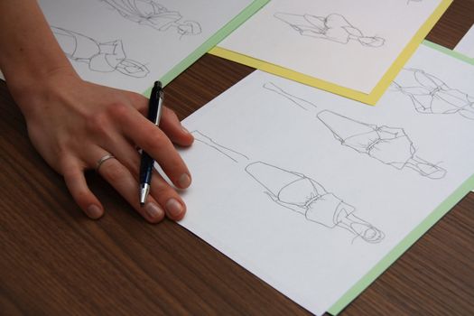 designer assessing fashion drawings on the collection of clothes