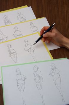 designer assessing fashion drawings on the collection of clothes