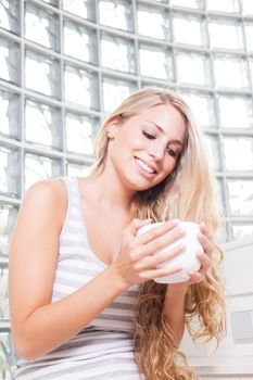 young beautiful woman drinks coffee on white cup