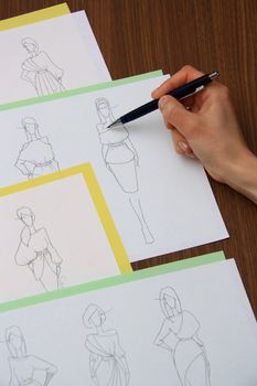 designer assessing fashion drawings on the collection of clothes