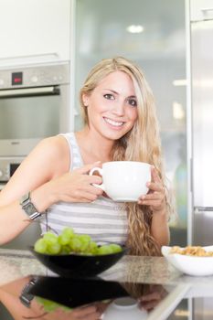 Young beautiful woman having a healthy breakfast in the kitchen