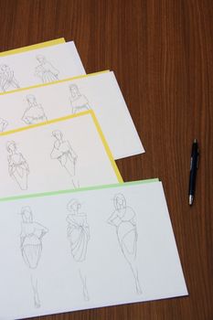 designer assessing fashion drawings on the collection of clothes