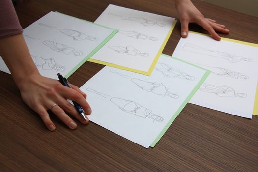 designer assessing fashion drawings on the collection of clothes