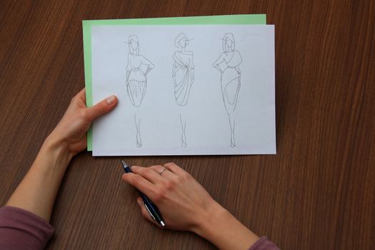 designer assessing fashion drawings on the collection of clothes