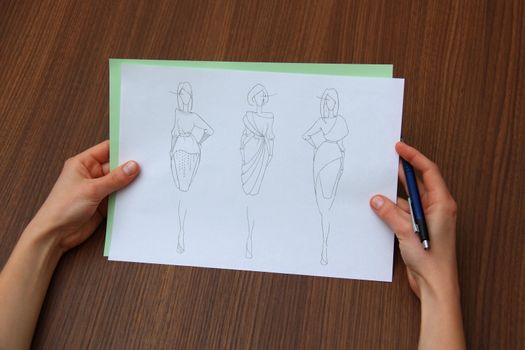 designer assessing fashion drawings on the collection of clothes