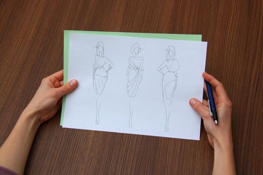 designer assessing fashion drawings on the collection of clothes