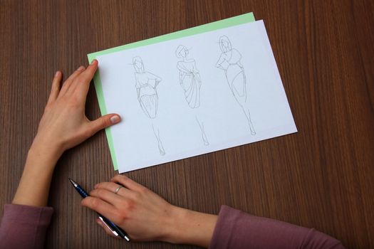 designer assessing fashion drawings on the collection of clothes