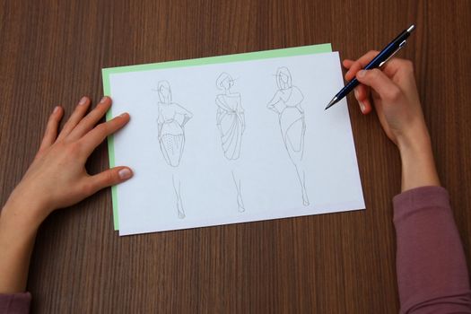 designer assessing fashion drawings on the collection of clothes