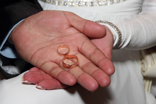 Wedding rings in hands of the newlyweds