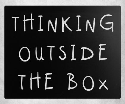 Thinking outside the box phrase, handwritten with white chalk on a blackboard