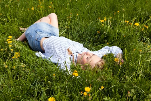 young woman lying in green gras happy