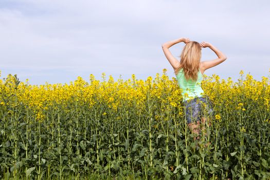 young beautiful blonde girl in a field in summer happy