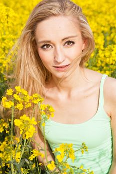 young beautiful blonde girl in a field in summer happy