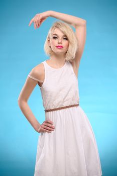 Sensual portrait of a beautiful blonde hair woman with white dress on blue background