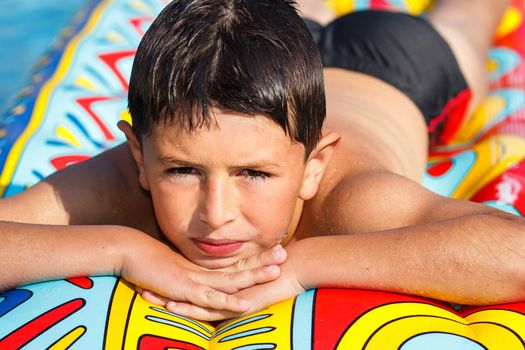 Boy with inflatable water lounger in the swimming pool