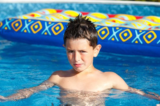 Boy with inflatable water lounger in the swimming pool