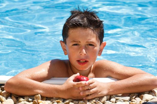 Boy eating fruit in the swimming pool