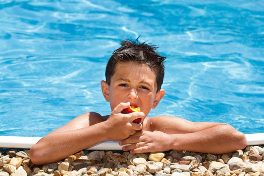 Boy eating fruit in the swimming pool