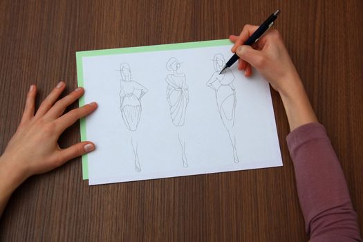 designer assessing fashion drawings on the collection of clothes