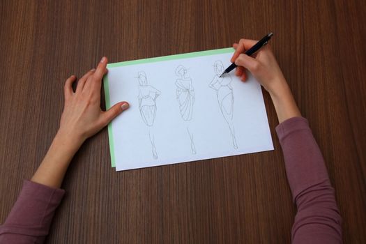 designer assessing fashion drawings on the collection of clothes