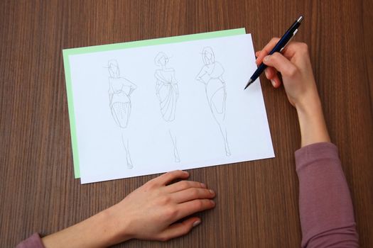 designer assessing fashion drawings on the collection of clothes