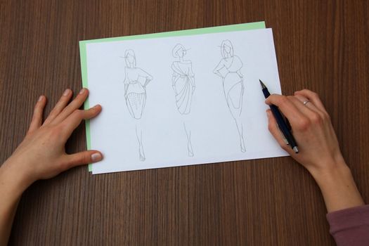 designer assessing fashion drawings on the collection of clothes