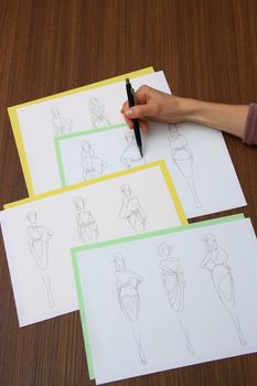 designer assessing fashion drawings on the collection of clothes