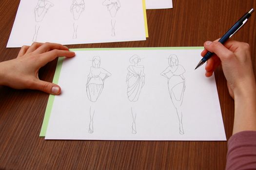 designer assessing fashion drawings on the collection of clothes