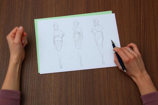 designer assessing fashion drawings on the collection of clothes