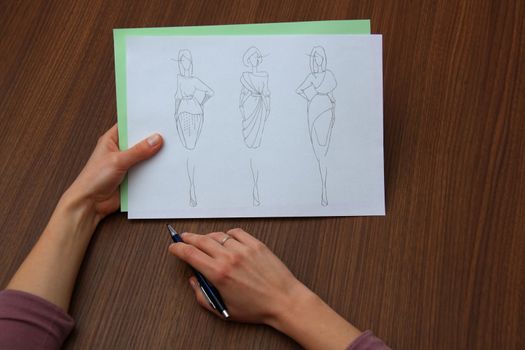 designer assessing fashion drawings on the collection of clothes