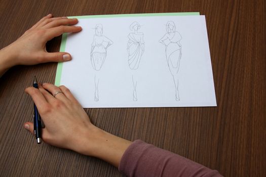 designer assessing fashion drawings on the collection of clothes