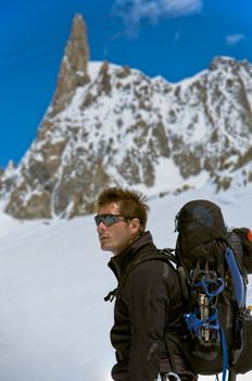 A male climber , dressed in black, climbs up a snowy slope. Winter clear sky day.