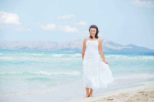Handsome young woman walking near blue sea.