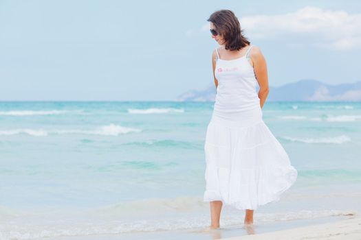 Handsome young woman walking near blue sea.