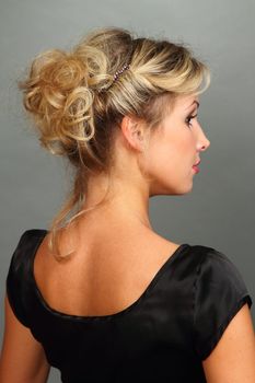 Portrait of the beautiful girl-blonde in a black dress with a magnificent hairdress.