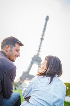 Young romantic couple sitting near the Eiffel Tower in Paris