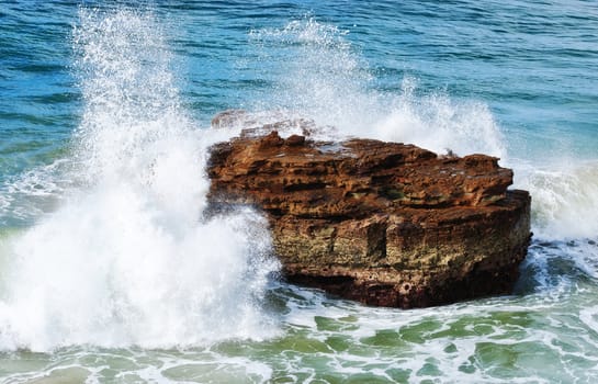 ocean waves crash on to rocks at the coast