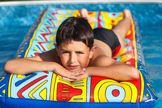 Boy with inflatable water lounger in the swimming pool