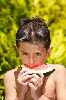 wet boy with watermelon in the garden after swimming