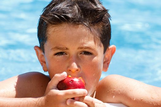 Boy eating fruit in the swimming pool